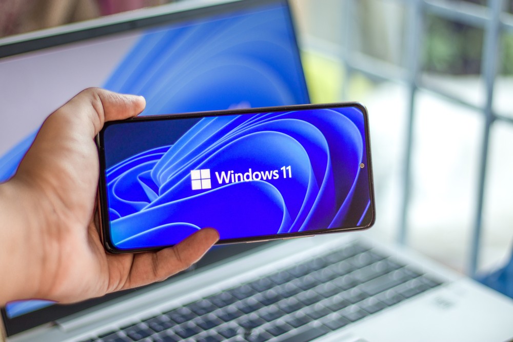 Hand holding a phone with Windows 11 logo