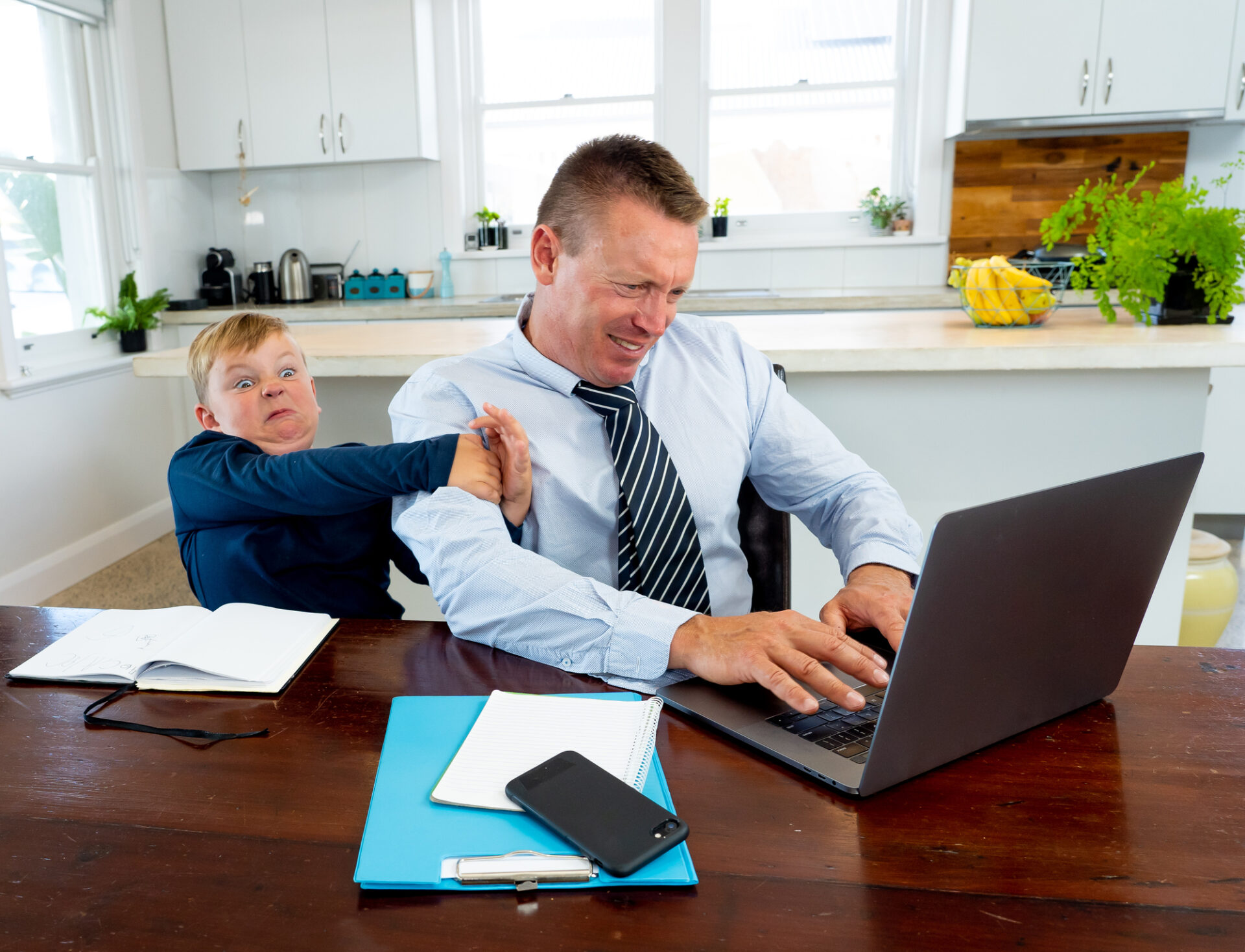 man getting pulled away from laptop by son