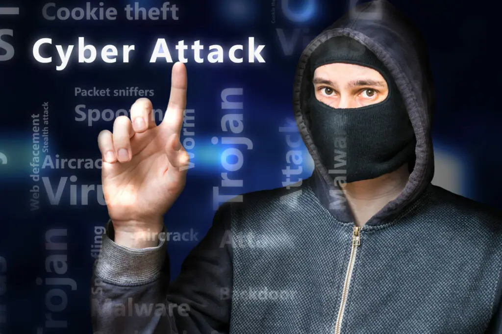 anonymous hacker pointing to the words cyber attacks