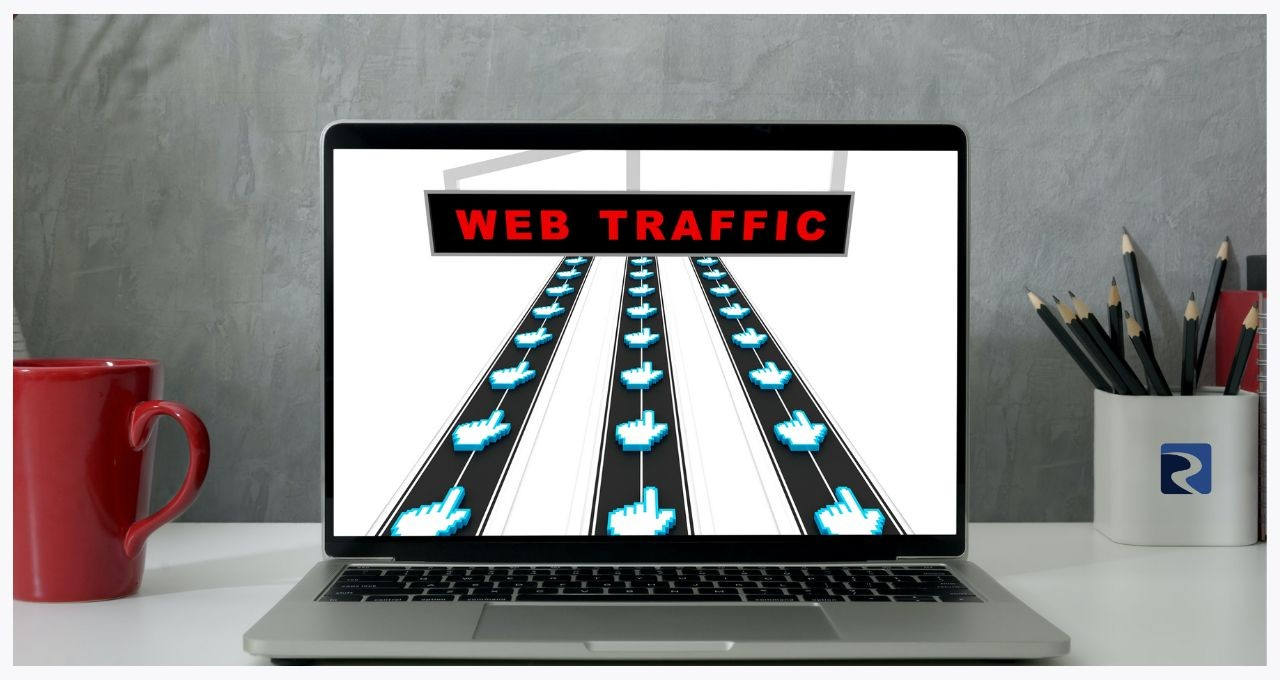 A laptop screen showing an image of mouse cursers traveling along roads and a sign reading "WEB TRAFFIC"
